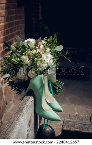 Wedding bouquet for the bride of white and pink flowers and stylish green shoes outdoor. Image for your creativity, design or illustrations.