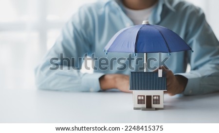 Individuals holding small umbrellas and model homes, housing insurance against impending loss and fire, building fire insurance, home and real estate insurance concepts. Royalty-Free Stock Photo #2248415375
