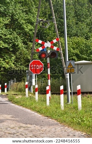 railway crossing on a forest road, the sign says not to touch the electric traction