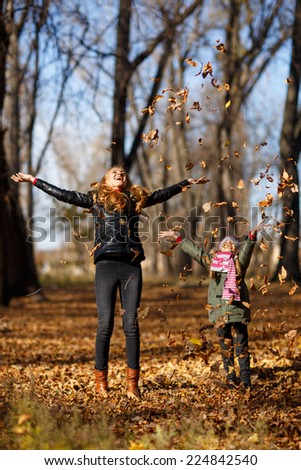 Young mother and her toddler girl in autumn park