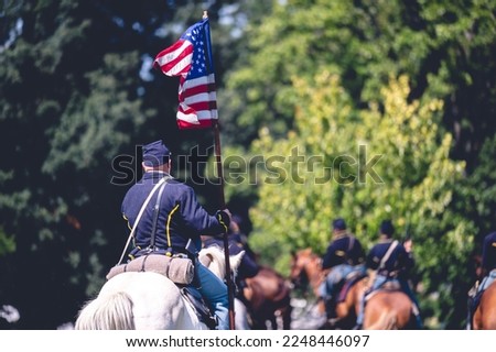 A soldier riding a horse and raises the flag of America during military performance in the Civil war reenactment in Jackson city, Michigan, USA