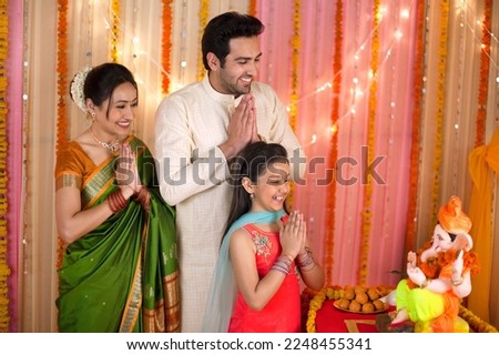 A happy Indian family seeking blessings from Lord Ganesha on Ganesh Chaturthi - Praying with folded hands. Stunning and beautiful family in Indian ethnic dress worshiping Lord Ganesha on Ganesh Cha... Royalty-Free Stock Photo #2248455341