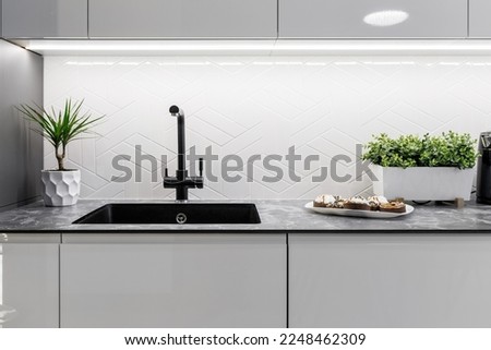 Black kitchen sink and Tap water in the kitchen. The interior of the kitchen room of the apartment. Built-In Appliances. Kitchen Appliance. Domestic Appliances Royalty-Free Stock Photo #2248462309