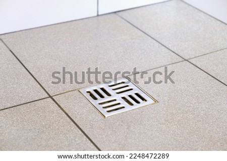 Water drain hole. Clean bathroom sewer trap. Close-up. Shower sewerage. Bath plug. Metallic grate. Anti-odor. Valve. Gray tile. Copy space. Royalty-Free Stock Photo #2248472289