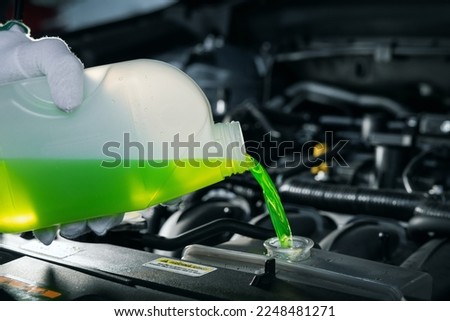 pouring antifreeze coolant liquid into car engine radiator Royalty-Free Stock Photo #2248481271