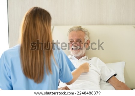 Man being cared for by a private Asian nurse at home suffering from Alzheimer's disease to closely care for elderly patients with copy space on left