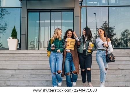 Front view of four college students walking out the college building