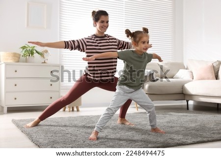 Young mother and her daughter practicing yoga together at home Royalty-Free Stock Photo #2248494475
