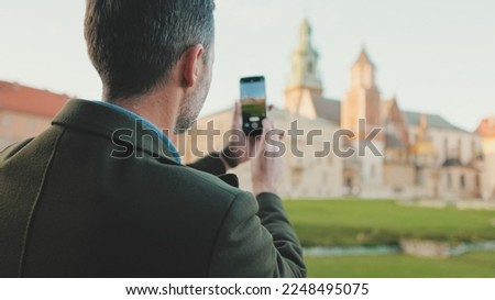 Man takes photo on mobile phone in the old city. Back view