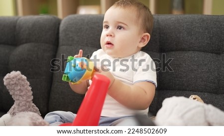Adorable toddler playing with toys sitting on sofa at home