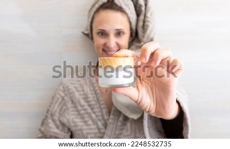 woman showing in front a cream to hydrate after bath or shower Royalty-Free Stock Photo #2248532735