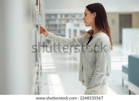 Woman, student and decision in library for book knowledge or learning at the university for education. Female looking at bookshelf in study, choice or assignment project for college scholarship