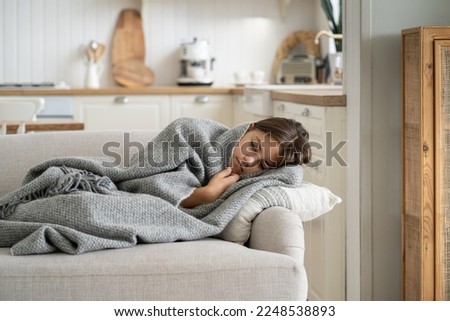 Unwell daughter lying on sofa at home while mom on work. Upset child girl feels exhaustion have day nap wrapped in blanket lack of energy after school day think about bullying problem with classmates Royalty-Free Stock Photo #2248538893