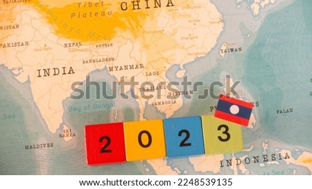 A map and flag of Laos with a block with 2023 written on it.