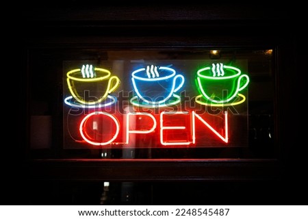 Neon open sign with coffee cup on glass door. an open cafe.