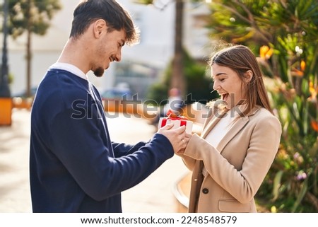 Mand and woman couple suprise with birthday gift standing together at park Royalty-Free Stock Photo #2248548579