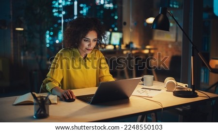 Portrait of a Focused Multiethnic Manager Working in Creative Office. Business-Driven Stylish Female with Curly Hair Using Laptop Computer for Making Online Work and Writing Financial Reports.