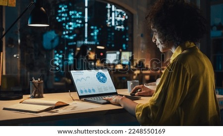 Creative Multiethnic Female Working on Laptop Computer with a Sales Statistics and Chart Displayed on Screen. Successful Designer Developing a Marketing Strategy, Preparing a Presentation Royalty-Free Stock Photo #2248550169