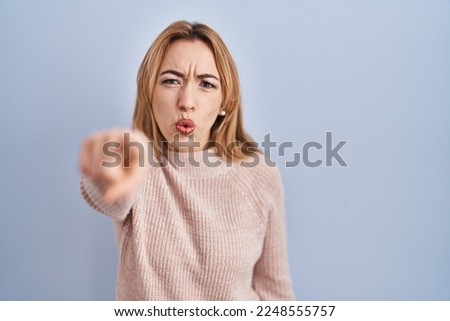Hispanic woman standing over blue background pointing displeased and frustrated to the camera, angry and furious with you 
