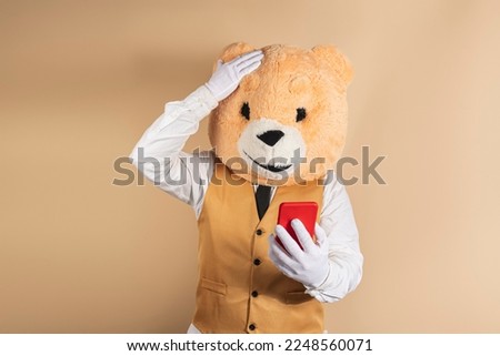 Excited man in bear mask reading good news on mobile phone on a yellow background.