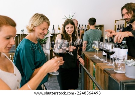 women participating to a blind wine tasting in winery checking wine color on glass listening to sommelier advice Royalty-Free Stock Photo #2248564493