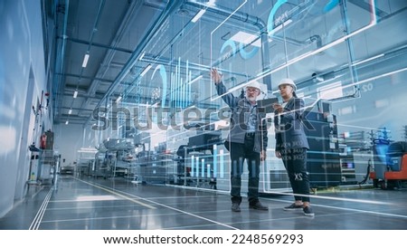 Factory Digitalization: Two Industrial Engineers Use Tablet Computer, Visualize the Wall of Big Data Statistics, Optimization of High-Tech Electronics Facility. Industry 4.0 Machinery Production Royalty-Free Stock Photo #2248569293