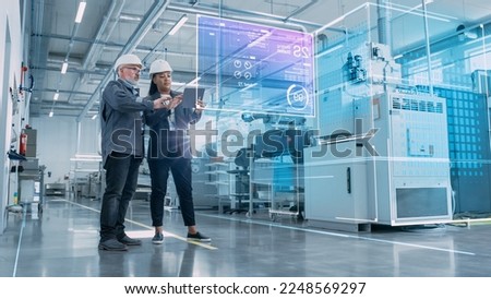 Factory Digitalization: Two Industrial Engineers Use Tablet Computer, Big Data Statistics Visualization, Optimization of High-Tech Electronics Facility. Industry 4.0 Machinery Manufacturing Products Royalty-Free Stock Photo #2248569297