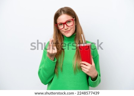 Young caucasian woman drinking soda isolated on white background making money gesture