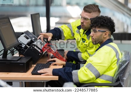 Two male engineers using desktop computer training Programmable logic controller or Programmable controller in the manufacturing automation and robotics academy room. Industrial computer concept Royalty-Free Stock Photo #2248577885