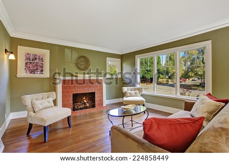 Olive tone family room with fireplace, two white chairs, sofa and glass top coffee table