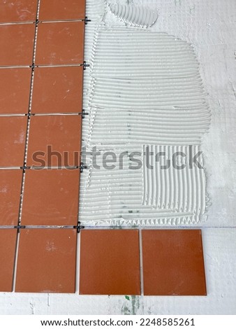 worker spreads the cement glue before applying the ceramic tiles
