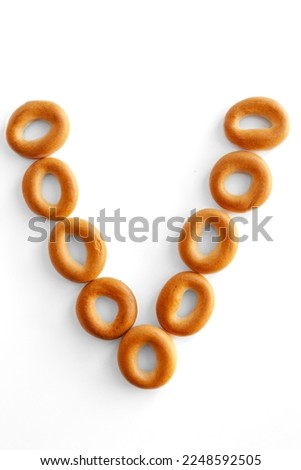Letter V bagel. Bagels font. Alphabet from set of small dry bagels isolated on white background. ABC symbols.