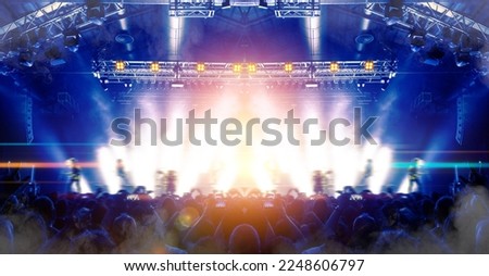 Image shot during a music festival. Light comes from a stage with a band show, people silhouettes are visible in front of it. Royalty-Free Stock Photo #2248606797
