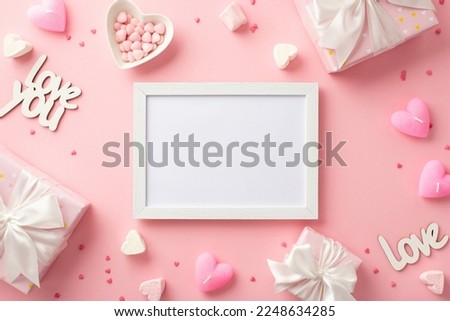 Valentine's Day concept. Top view photo of white photo frame gift boxes heart shaped saucer with sprinkles candles marshmallow and inscriptions love on isolated pastel pink background with blank space