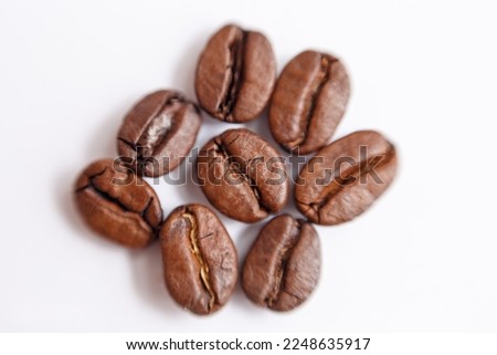 several grains of roasted coffee on a white background. macro. photographed with an old lens with blurring around the edges, and with a shallow depth of field. very large. High quality photo