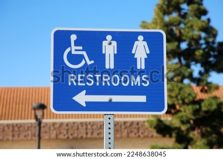 Restrooms. Bathroom Sign. Handicap, Men and Women Restrooms Sign. Restrooms to the left. Public Toilets. Blue Metal Sign on a metal post. Public Restrooms. 