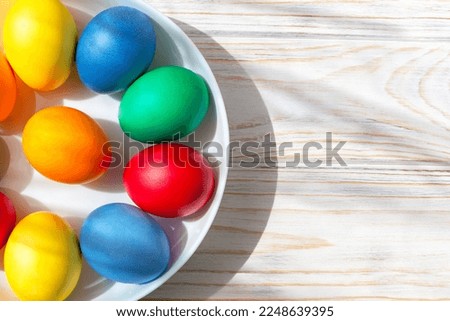 Easter. There are Easter eggs on a round white plate. White wooden background with copy space. Flat lay