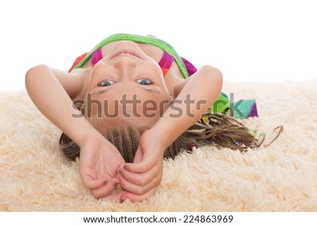 Happy little girl with dreadlocks lays on her back. Girl six years.