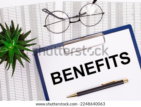 Folded business papers, pen, glasses, a flower in a pot and a tablet with a sheet of paper with the text BENEFITS on the desktop. Top view of the workplace. Business concept