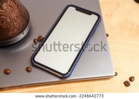 the Turk stands on a laptop, coffee beans are scattered around and a phone with a white color inside. High quality photo