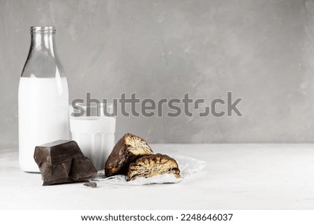 poppy seed buns in chocolate with a bottle of milk and a glass close-up on a gray background with copy space