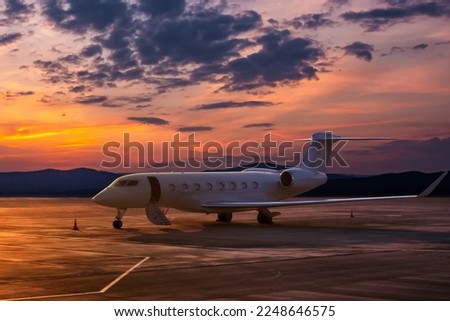 Modern executive aircraft with an opened gangway at the airport apron on the background of a scenic dawn Royalty-Free Stock Photo #2248646575