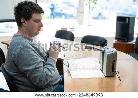 A visually impaired man uses a scanning and reading machine. Royalty-Free Stock Photo #2248649393