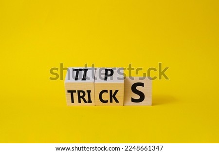 Tips and Tricks symbol. Wooden cubes with words Tricks and Tips. Beautiful yellow background. Business and Tips and Tricks concept. Copy space