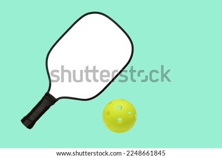 Pickleball paddle and pickleball ball on a blue background. White racket for your design.