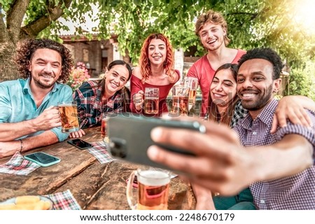 Happy friends drinking beer at outdoor brewery bar - Group of multiracial people taking selfie during ale toast - Friendship lifestyle concept young millennials having fun together at outdoor pub	
