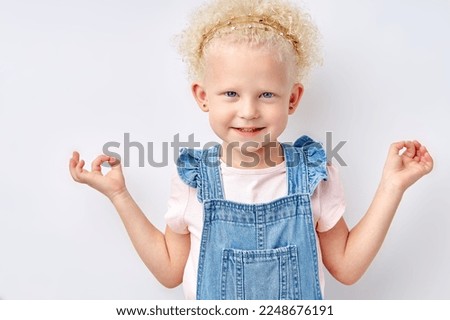 calm child girl meditating isolated on white studio background. cute caucasian kid in dress posing looking at camera, copy space for advertisement. keep calm. meditating, yoga, children