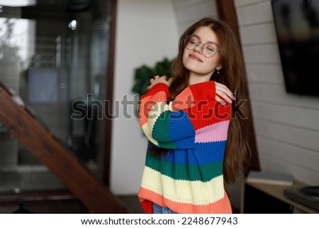 Young attractive woman hugging herself in a home interior, dressed in a warm sweater. Royalty-Free Stock Photo #2248677943