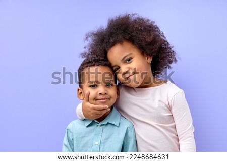 Photo of two young little black kids happy positive smile embrace family together isolated over violet purple color background. beautiful cildren in casual outfit love each other, hugging Royalty-Free Stock Photo #2248684631