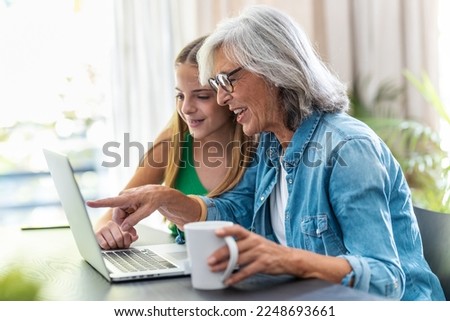 Shot of happy granmother shopping online with credit card using laptop with her granddaughter at home.